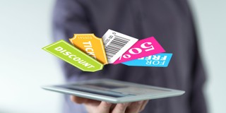 Une main tient une tablette sur laquelle flottent des étiquettes colorées de réduction et de tickets avec des mots comme réduction, ticket et 500.