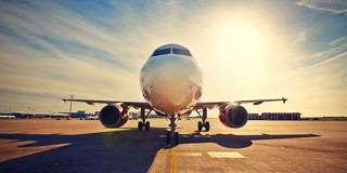 Un avion est stationné sur un aéroport avec le soleil qui brille intensément en arrière-plan.