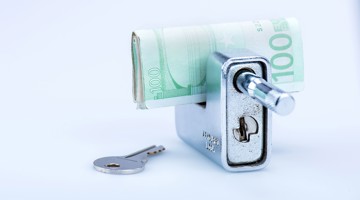 Un cadenas à chiffres argenté avec un billet de 100 euros à l'intérieur et une clé à côté.