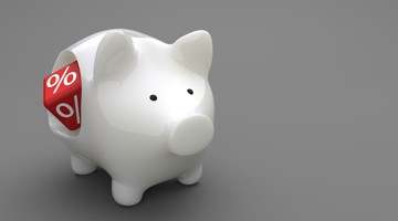 Tirelire blanche en forme de cochon avec une étiquette de réduction rouge comportant un symbole de pourcentage.