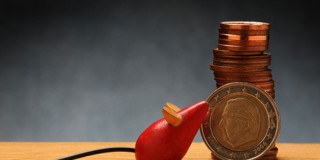 Une pile de pièces à côté d'un micro jouet rouge posé sur une table en bois.