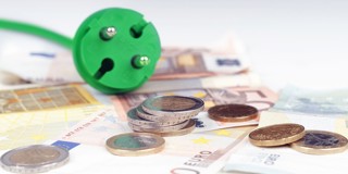 Une prise verte repose sur une pile de billets en euros et de pièces, illustrant la relation entre l'énergie et les coûts.