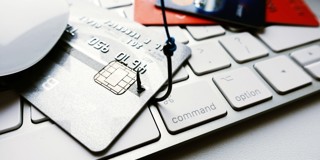 Een zilveren bankpas ligt op een laptoptoetsenbord, omringd door andere kredietkaarten en een computermuis.