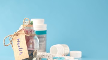 Un bocal en verre rempli d'argent avec l'étiquette 'Santé', accompagné de plusieurs pilules et médicaments sur un fond bleu.
