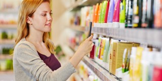 Een vrouw staat in een winkel en kijkt naar verschillende haarproducten op een plank.