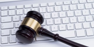 Un marteau de juge repose sur un clavier d'ordinateur, symbolisant la combinaison du droit et de la technologie.