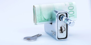 Een 100 euro biljet wordt in een slot gestoken, met een sleutel ernaast.