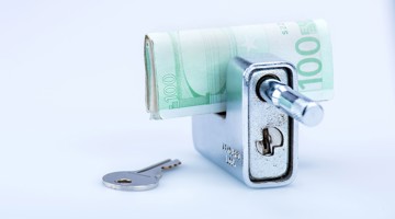 Een 100 euro biljet wordt in een slot gestoken, met een sleutel ernaast.