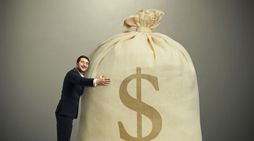 Een man in een pak omarmt een grote zak met geld met een dollar-symbool erop.
