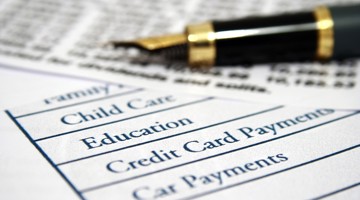 Een gestructureerd document met een lijst van uitgavencategorieën zoals kinderopvang, onderwijs en creditcardbetalingen, naast een luxe vulpen.