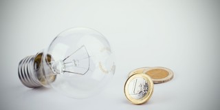 Een gloeilamp ligt naast twee munten van twee euro.