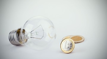 Een gloeilamp ligt naast twee munten van twee euro.