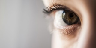 Close-up van een oog met hazelnootkleurige iris en lange wimpers.