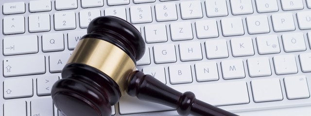 Een houten hamer met een gouden ring ligt op een computertoetsenbord.