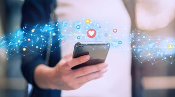 Une personne tient un smartphone, entourée d'un réseau numérique d'icônes de médias sociaux et de cœurs.