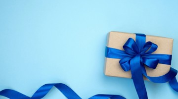 Bruine cadeauverpakking met een blauwe strik op een lichtblauwe achtergrond.