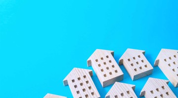 Cinq icônes de maisons en bois clair disposées sur un fond bleu.