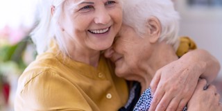 Deux femmes âgées s'enlacent avec une expression d'amour, dans une atmosphère de connexion et d'attention.