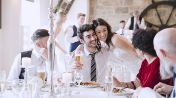 Un groupe d'invités profitant d'une réception de mariage autour d'une table, avec de la nourriture et des boissons.