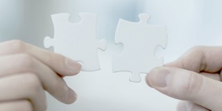 Deux pièces de puzzle blanches sont maintenues ensemble.